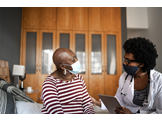 A physician speaking with an older adult patient in her home